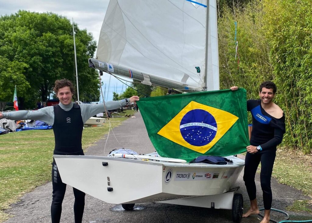 Bernardo peixoto e Gustavo baiano segurando a bandeira brasileira perto do snipe